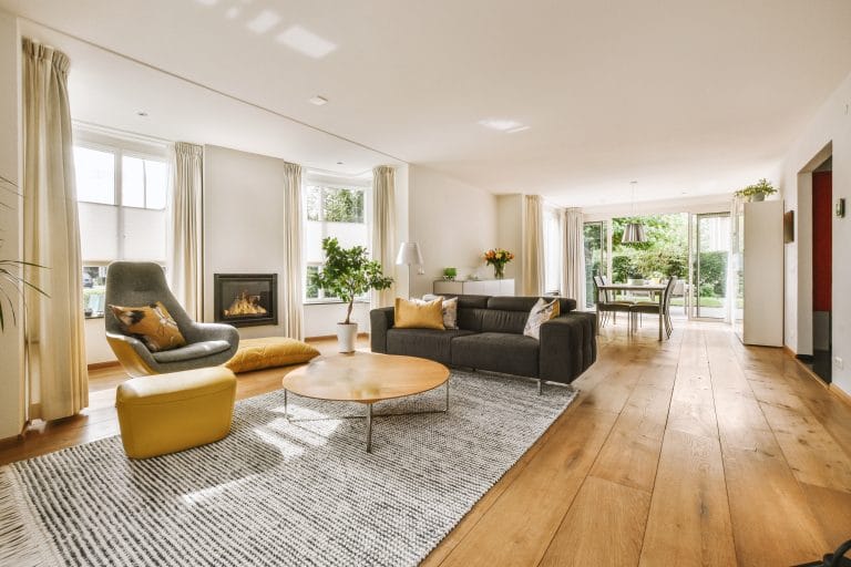 Contemporary minimalist style interior design of light studio apartment with wooden table and chairs in dining zone between open kitchen and living room with white walls and parquet floor